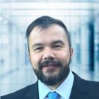 Mężczyzna z zarostem, białej koszuli, krawatem i w marynarce