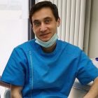 Lekarz w niebieskim uniformie i maseczce ściągniętej pod brodę