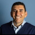 Uśmiechający się mężczyzna w szarej koszuli i niebieskim swetrze