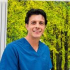 Lekarz spoglądający w obiektyw ubrany w niebieski uniform